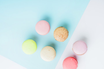 An overhead view of colorful macaroons on blue and white dual background