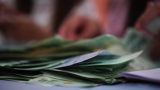 Businesswoman's hands counting hundred thai baht bills banknotes at a table in bank. (THB) is the official currency of Thailand, slow motion