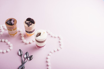 White pearls necklace and spoons near the chocolate and vanilla pudding in glasses