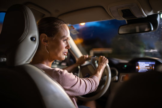 Young female driver driving her car at night (color toned image; shallow DOF)