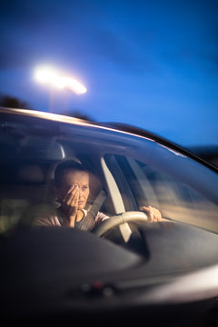 Young female driver at the wheel of her car, super tired, falling asleep while driving in a potentially dangerous situation - Road safety concept