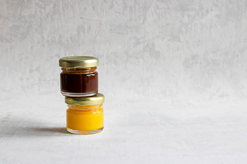 Two Small glass jar with metal cap with light yellow and dark brown honey one on another isolate on...