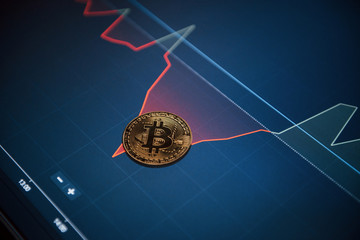 Conception of new era of currency. Picture of golden bitcoin lying on the display with graphs in office