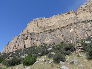 Close up, side view of imposing rocky wall cliffs along the road through Bighorn Mountains in Wyoming, with beautiful clouds in the skies.