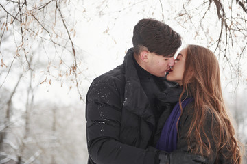 Lovely kisses. Gorgeous young couple have good time together in snowy forest
