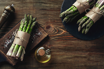 An edible, raw stems of asparagus on a wooden background.
