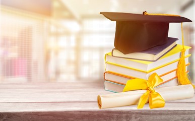 Graduation mortarboard on top of stack of books on  background