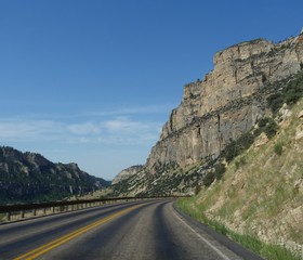 Imposing rocky wall cliffs along the road through Bighorn Mountains in Wyoming, with beautiful clouds in the skies.