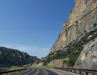 Medium wide, side view shot of tall steep rocky walls along the road through Bighorn Mountains in Wyoming, USA.