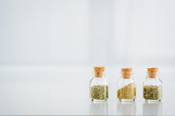 corked jars with dried herbs on white background with copy space