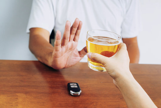 Do not drink and drive! Cropped image of man showing stop gesture and refusing to drink beer. Car keys lying near .Don't drink and drive concept