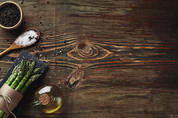 An edible, raw stems of asparagus on a wooden background.