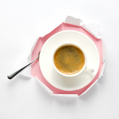 Paper hole in white paper and cup of coffee on pink background.