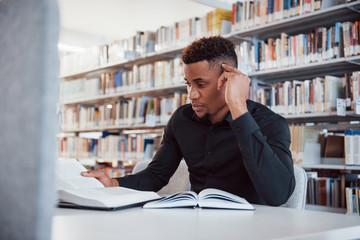 Tired by searching right information. African american man sitting in the library