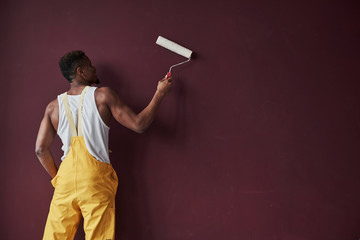 Nice velvet wall. Young african american worker in the yellow uniform have some job