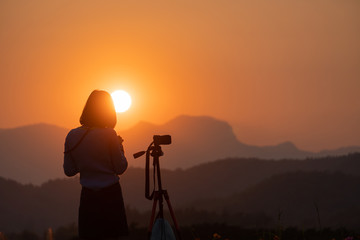 silhouette of photographer in sunset with mountain background 