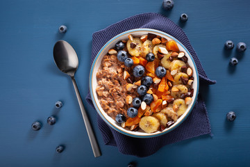 chocolate oatmeal porridge with blueberry, nuts, banana, dried apricot for healthy breakfast. Top...