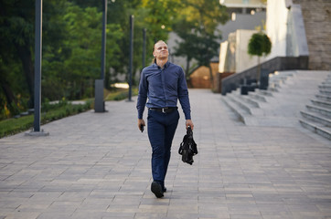 Serious businessman walking on cityscape background. The best day. Young man in formal wear walking...