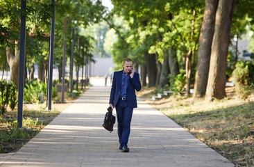Serious businessman walking on cityscape background. The best day. Young man in formal wear walking...