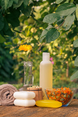 Towel, soap with marigold extract, calendula flowers in a flask with natural background.