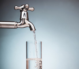 water is poured into a glass from the tap