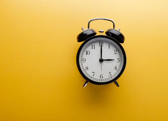 Alarm clock on yellow background top view. Concept of time.