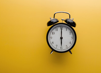 Alarm clock on yellow background top view. Concept of time.