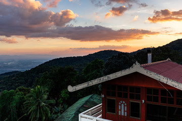 Scenic forest and mountains with a facade of the traditional buddhist wooden building in remote area of Thailand