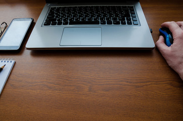 Business man using laptop computer hand typing on laptop keyboard with notebook pen glasses