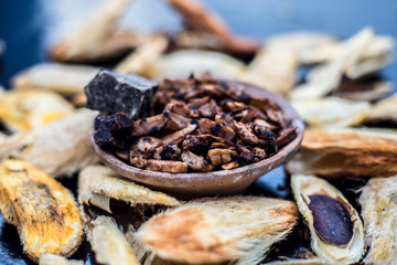 Popular Indian and Asian mukhwas or mouth freshener i.e. Aam Ki Ghuthli Ka Mukhwas consisting of ghee and hard-boiled mango seeds in a bowl on a wooden surface.Along with some raw dried mango seeds.