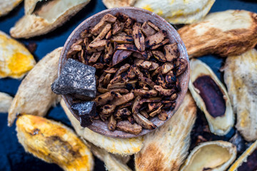 Popular Indian and Asian mukhwas or mouth freshener i.e. Aam Ki Ghuthli Ka Mukhwas consisting of ghee and hard-boiled mango seeds in a bowl on a wooden surface.Along with some raw dried mango seeds.