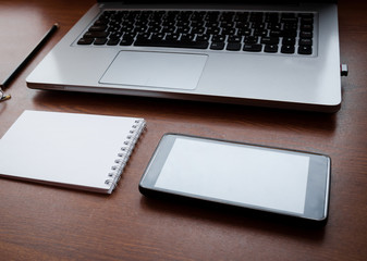 Wood office desk table with laptop, notebook, pen, smartphone. Top view, copy space