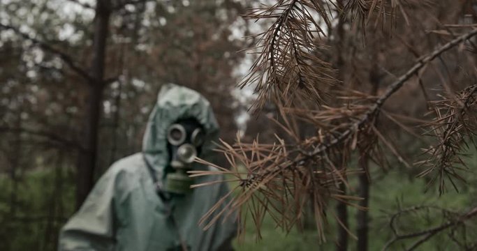Person in WWII Hazmat suit and gas mask checking for contamination in a forest plantation with a counter and probe. Reconstruction of the events of the Chernobyl catastrophe on April 26, 1986
