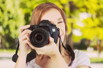 Woman-photographer with black digital camera on a natural background
