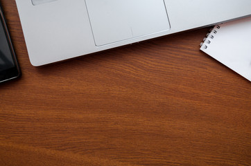 Wood office desk table with laptop, glasses, notebook, pen, smartphone. Top view, copy space
