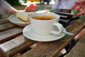 Tasse Kaffee mit Kuchen und Handy im Hintergrund im Straßencafe