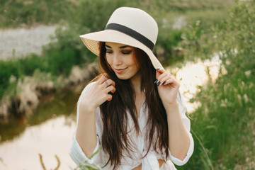 Beautiful carefree long hair asian girl in white clothesand straw hat  on river side in the grass...
