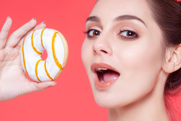 Beautiful young cheerful girl bites donut