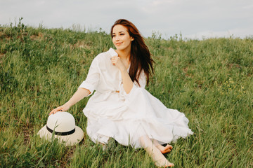 Charming carefree long hair asian girl in white clothes and straw hat enjoys life in the field at...