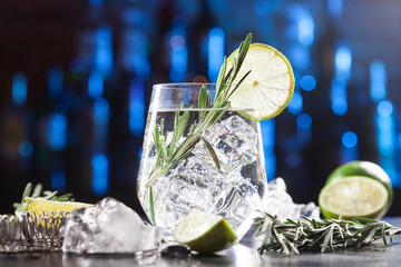 Glass with alcoholic drink with lime, ice and rosemary