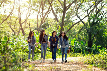 Naklejka na ściany i meble Group of women walking through woodland.Group of women smiling walking with backpack.travel and hike concept