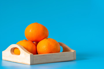 Summer of orange fruit in wood box on blue background.