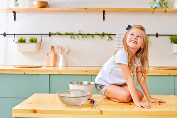 Cheerful little girl sitting on kitchen table