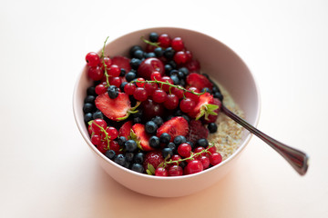 Porridge bowl oatmeal with berries on pink background. Soft focus. Healthy eating concept. Front view