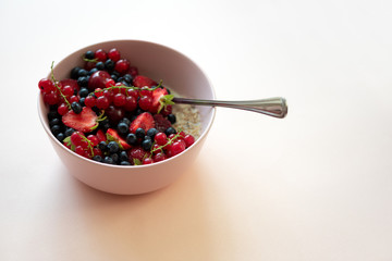 Porridge bowl oatmeal with berries on pink background. Soft focus. Healthy eating concept. Front view