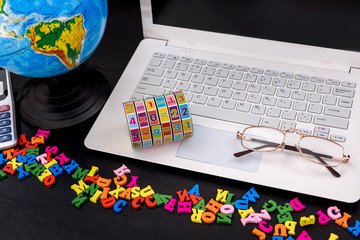 Laptop with colorful alphabet and globe on table