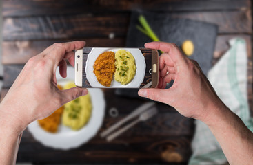 Man taking photo of Chicken steak or schnitzel with mashed potatoes