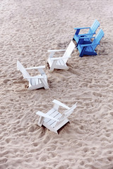 Blue and white plastic deckchairs on the white sands of a beach