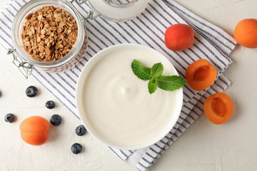 Composition with granola, yogurt and fresh fruits on white cement background