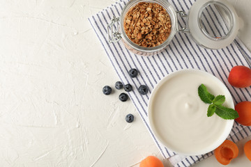 Composition with granola, yogurt and fresh fruits on white cement background